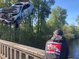 Dive team member watches car being hoisted onto bridge deck