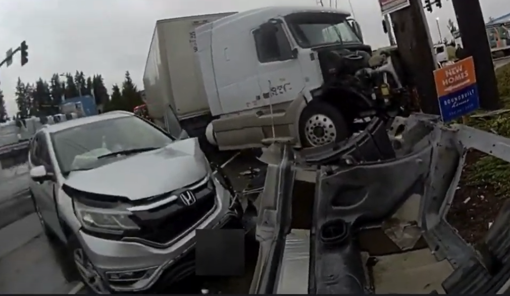 Deputy's body-worn camera shows a vehicle with front-end damage and a semi-truck resting against a utility pole